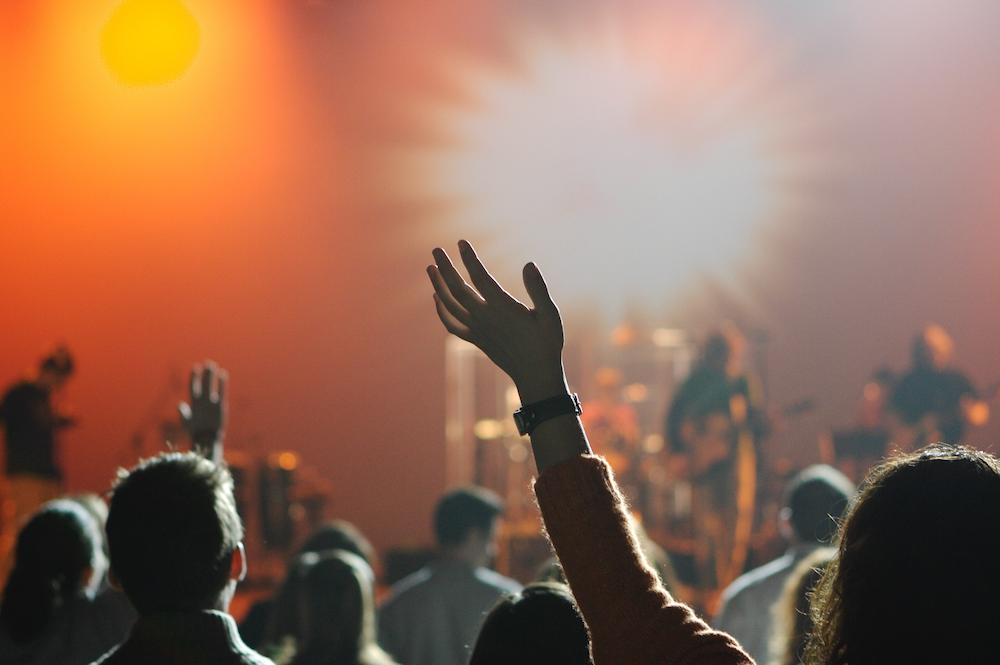 A group of Christians worship God with their hands raised.