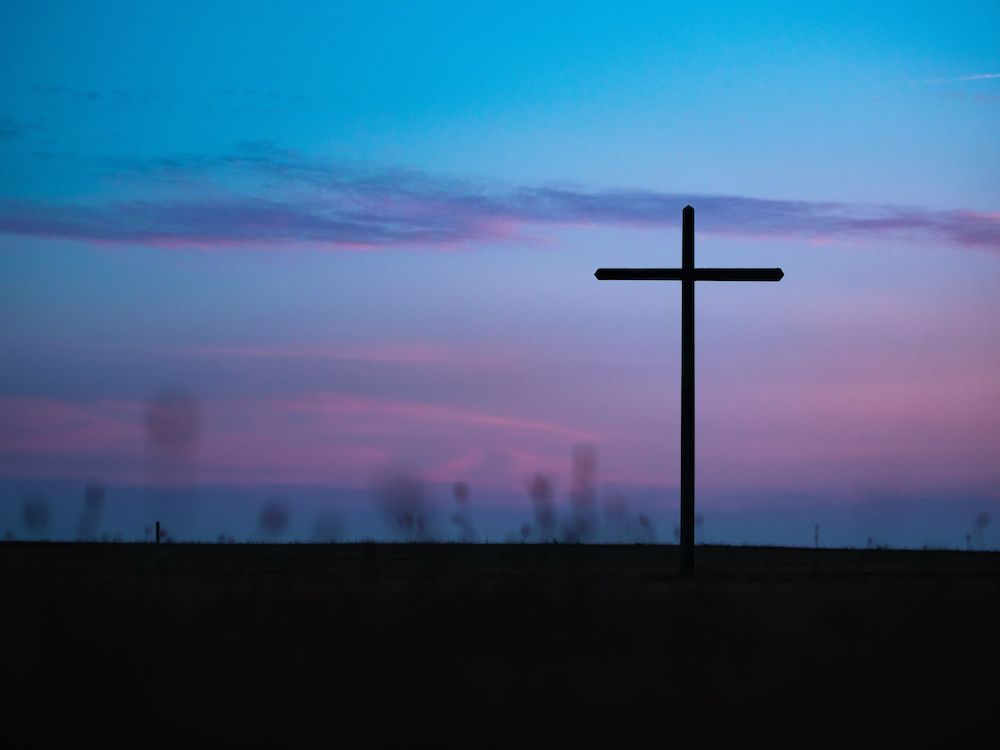 A cross stands alone at dusk.